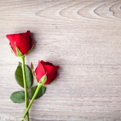 two red roses on a wooden table
