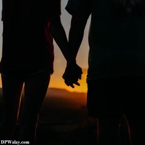 a couple holding hands at sunset