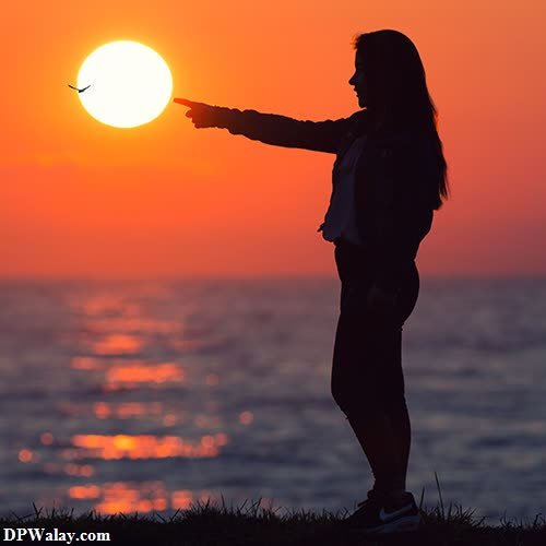 a woman is pointing at the sun
