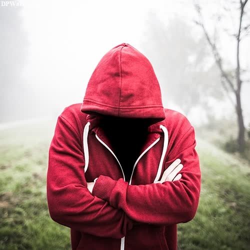 a person in a red hoodie standing in the fog