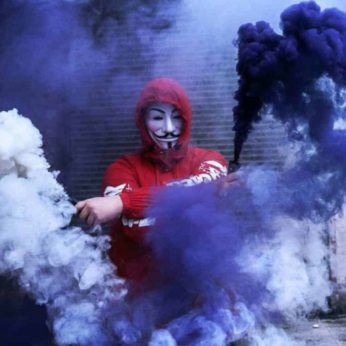 a man in a red hood and mask is smoking smoke 