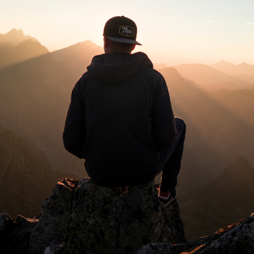 a man sitting on a rock looking out at the mountains