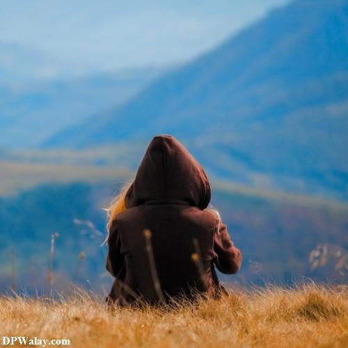 a person sitting in a field with mountains in the background