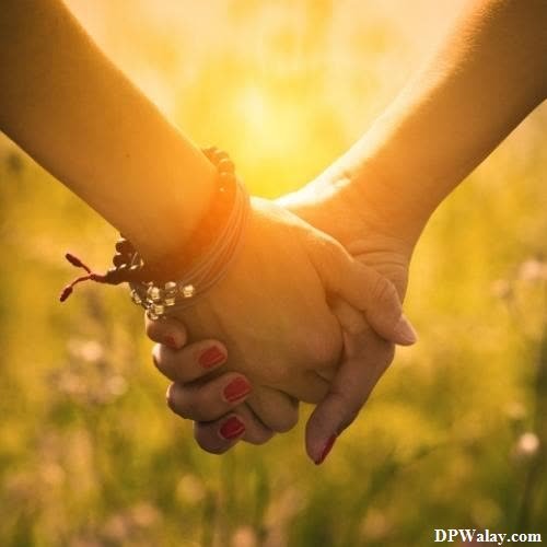 two people holding hands in a field