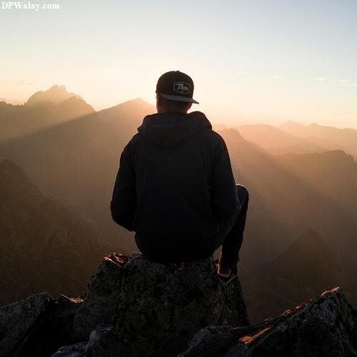 a man sitting on top of a mountain looking out at the sunset