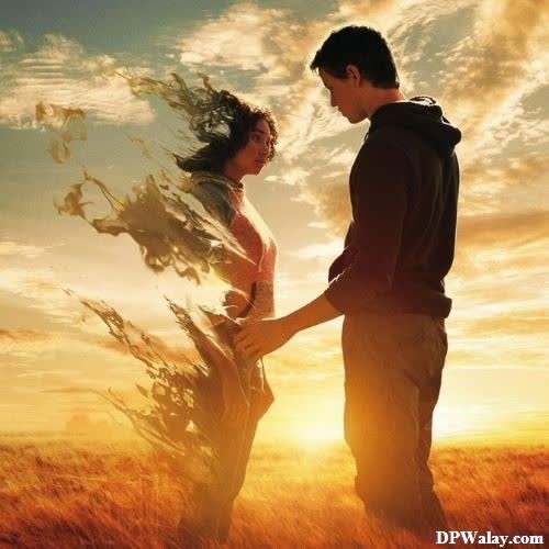 a couple standing in a field with the sun setting behind them