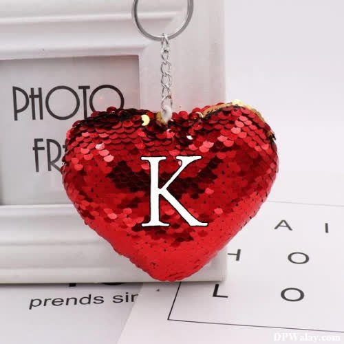 a red heart shaped keychai with the letter k on it