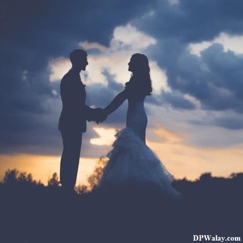 a bride and groom standing in front of a sunset