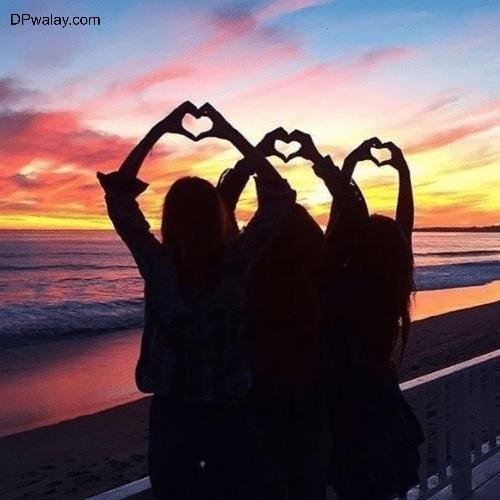 two girls making a heart with their hands at the beach images by DPwalay